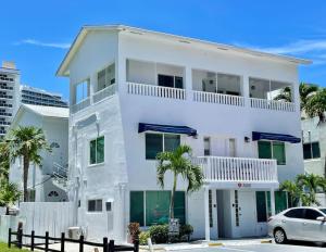 Ocean Breeze Paradise Apt 5A في فورت لاودردال: بيت أبيض مع سيارة متوقفة أمامه