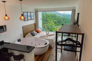 a bathroom with a tub and a bed and a window at Alto da Piraquara Flat in Angra dos Reis