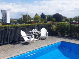 twee stoelen en een tafel naast een zwembad bij 52 on Rifle Motel in Taupo