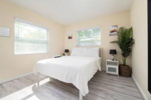 a white bedroom with a bed and a potted plant at Short Walk to Wilton Drive Apt6 in Fort Lauderdale