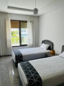 a hotel room with two beds and a window at Harhoura Modern Flat in Temara