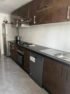 a kitchen with brown cabinets and a stove and a sink at Harhoura Modern Flat in Temara