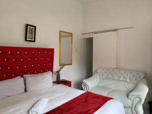a bedroom with a red headboard and a white bed at Beach View B&B in East London