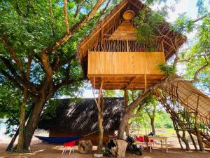 una casa en el árbol con una hamaca en un árbol en Yala Village Eco Tree House, en Tissamaharama