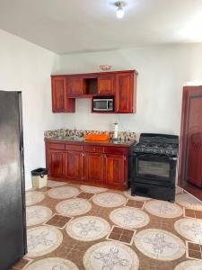uma cozinha com armários de madeira e um fogão em Veronica Homestay Lucea Jamaica em Lucea