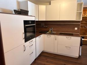 a kitchen with white cabinets and a black appliance at Appartement Everest in Zermatt