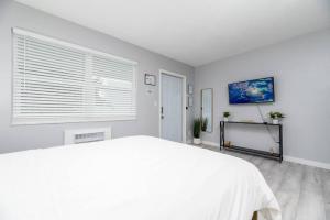 a white bedroom with a bed and a window at Just Off Wilton Drive Apt 5 in Fort Lauderdale