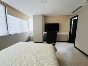 een slaapkamer met een bed en een flatscreen-tv bij SUITE TORRES BELLINI, PUERTO SANTA ANA in Guayaquil