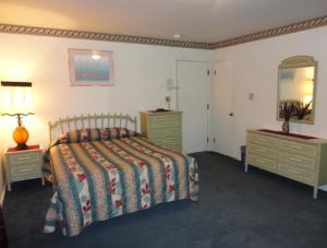 a bedroom with a bed and two dressers and a mirror at Theater Motel in Westfield
