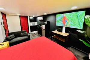 1 dormitorio con cama roja y TV de pantalla plana en New Tiny Home Uptown Phoenix (Unit E), en Phoenix