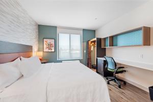 圣贝纳迪诺Home2 Suites By Hilton San Bernardino的一间卧室，配有一张床、一张桌子和一把椅子