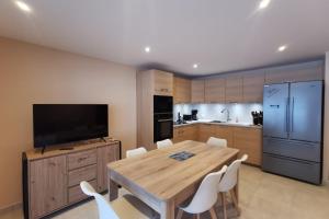 une cuisine avec une table en bois et des chaises blanches dans l'établissement L'écrin des neiges - Sauna, à La Féclaz