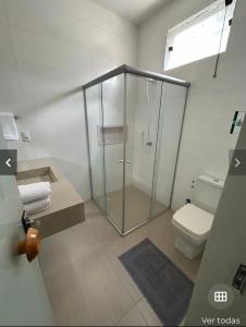 uma casa de banho com uma cabina de duche em vidro e um WC. em Hospedagem aconchegante com área gourmet em Araguaína