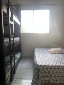 Cette petite chambre comprend 2 lits et une fenêtre. dans l'établissement Edifício Malibú, à Praia Grande