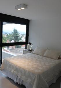 a bedroom with a large bed with a large window at Departamentos Ciudad de Nieva in San Salvador de Jujuy