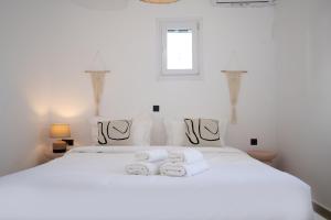 ein Schlafzimmer mit einem weißen Bett und Handtüchern darauf in der Unterkunft Loom Suite Ornos in Mykonos Stadt