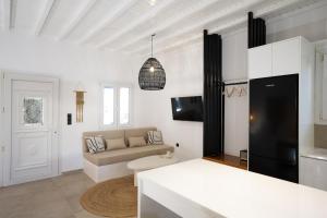 a white living room with a couch and a tv at Loom Suite Ornos in Mikonos