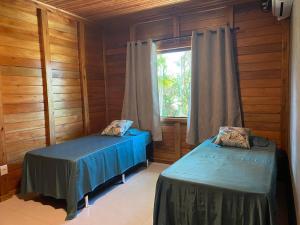 two beds in a room with a window at Cabana das Mandalas in Itacaré