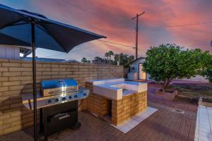 a barbecue grill with an umbrella on a brick patio at New Midtown Modern Studio With Backyard (Unit B) in Phoenix
