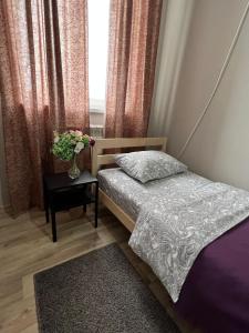 Un dormitorio con una cama y una mesa con un jarrón de flores en Гостевой Отель-125 en Aktau