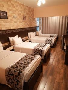 Al-Naher Al-Khaled Hotel في العقبة: غرفة في فندق بثلاث اسرة في غرفة