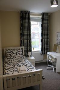 Schlafzimmer mit einem Bett, einem Schreibtisch und einem Fenster in der Unterkunft Station Rooms in Londonderry County Borough