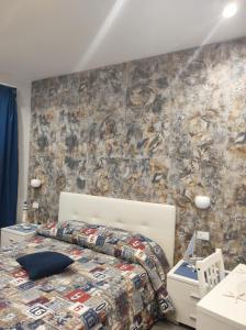 1 dormitorio con cama y pared de piedra en B&B La Grotta en Nicolosi