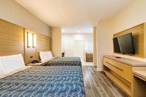 a hotel room with two beds and a flat screen tv at Palace Inn Blue-IAH East in Humble