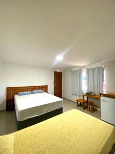 a bedroom with two beds and a table and a kitchen at Praieira Hostel&Pousada in Itacaré