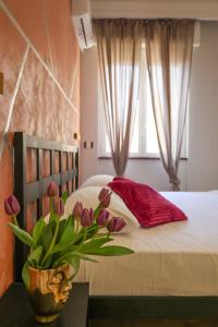 a bedroom with a bed with a vase of flowers on a table at Cuore Napoli Centro in Naples