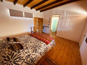 1 dormitorio con 1 cama y suelo de madera en Atacama Checar, Hostal, en San Pedro de Atacama