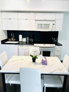 a white kitchen with a table and white appliances at Royal Suite in Toronto