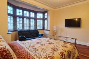 a bedroom with a bed and a couch and a television at Luxury London House Sleeps x 16, Free Parking, Free Wifi, Garden Patio, Close to tube line easy access to Central London in Ilford