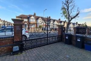 a black fence with a gate with trash cans at Luxury London House Sleeps x 16, Free Parking, Free Wifi, Garden Patio, Close to tube line easy access to Central London in Ilford