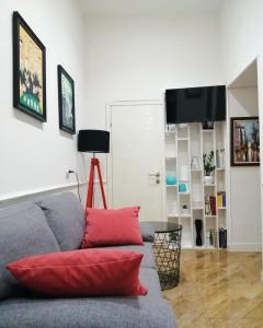 uma sala de estar com um sofá cinzento com almofadas vermelhas em Sleep Hostel em Niš