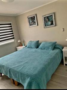 a bedroom with a large bed with a blue comforter at Cómodo, tranquilo y acogedor. in Caldera