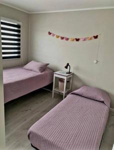 a bedroom with two beds and a table with a lamp at Cómodo, tranquilo y acogedor. in Caldera