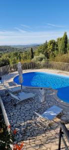 einen Pool mit 2 Stühlen und einem Sonnenschirm in der Unterkunft Jolie Villa piscine vue mer in Tourrettes-sur-Loup