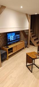 a living room with a large screen tv and stairs at Antares - SILS --- 2 chambres séparées en mezzanine in Caen
