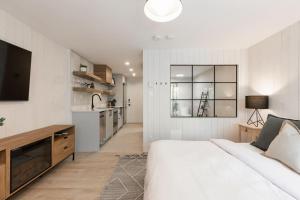a white bedroom with a large bed and a kitchen at Luxurious & Modern Tremblant Loft Pool&Spa Access in Mont-Tremblant