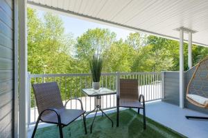 a screened porch with two chairs and a table at Luxurious & Modern Tremblant Loft Pool&Spa Access in Mont-Tremblant