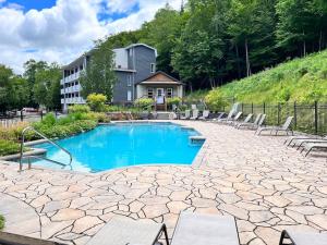a swimming pool with chairs and a building at Luxurious & Modern Tremblant Loft Pool&Spa Access in Mont-Tremblant