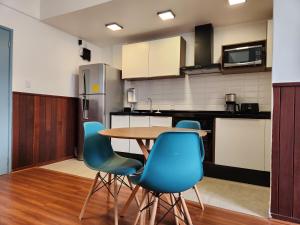 cocina con mesa de madera y sillas azules en Flat 335 - excelente localizacão, estacionamento, en Teresópolis