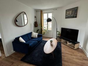 een woonkamer met een blauwe bank en een tafel bij Cosy appartement lumineux in Arcueil