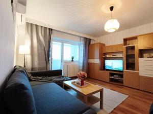 ein Wohnzimmer mit einem blauen Sofa und einem TV in der Unterkunft Sunrise Beachfront Relax Studio in Constanţa
