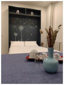 PIGRO House - Bologna Airport Suite في بولونيا: غرفة نوم بسرير و مزهرية زرقاء على طاولة