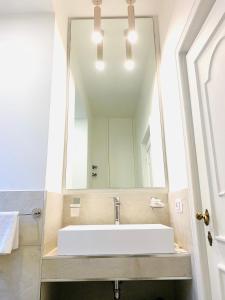 La salle de bains est pourvue d'un lavabo blanc et d'un miroir. dans l'établissement Ripetta Suite Apartament, à Rome