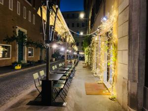 une rangée de bancs sur une rue la nuit avec des lumières dans l'établissement Ripetta Suite Apartament, à Rome