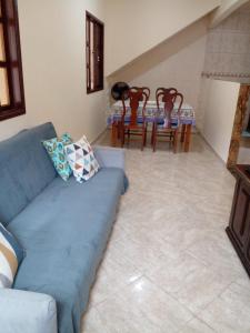 sala de estar con sofá azul, mesa y sillas en Caminho da Praia - Casa e kitnet en Arraial do Cabo