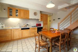 a kitchen with a wooden table and wooden cabinets at La Maison de Fernande in Gourgeon